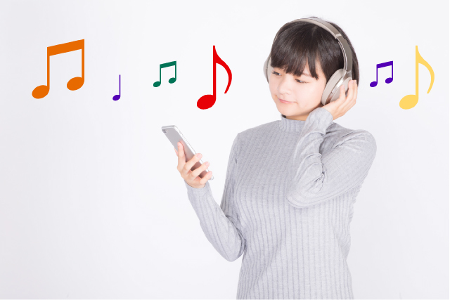 ヘッドホンをつけた女性の周りに、カラフルな音符がある